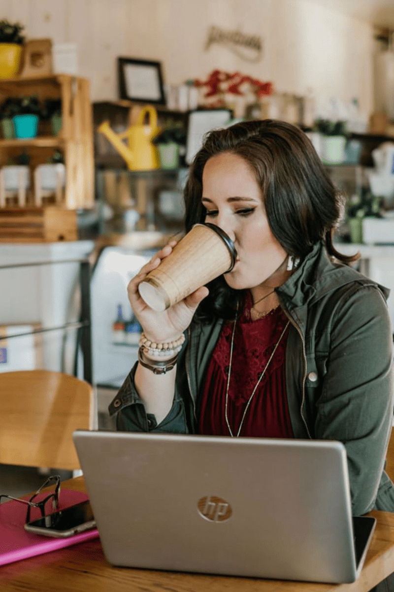 Me, sipping a coffee at a table, in front of my laptop